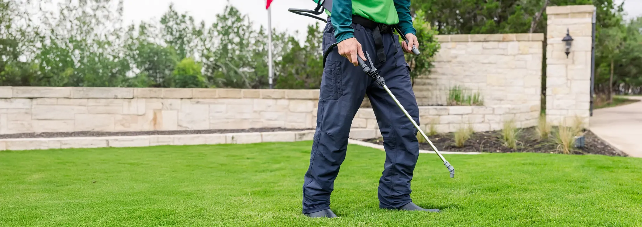 lawn technician spraying lawn for weeds